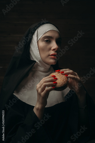 Canvastavla Attractive nun eating burger with indifferent expression on her face