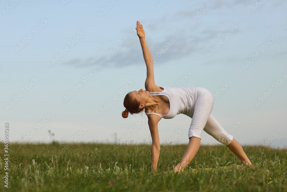 Fototapeta premium Adult woman doing yoga in summer spring countryside