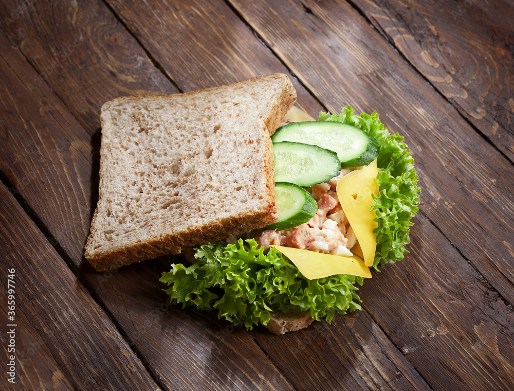 tuna sandwich with fresh green salad and cucumbers on rustic wooden table surface tuna sandwich with fresh green salad and cucumbers on rustic wooden table surface