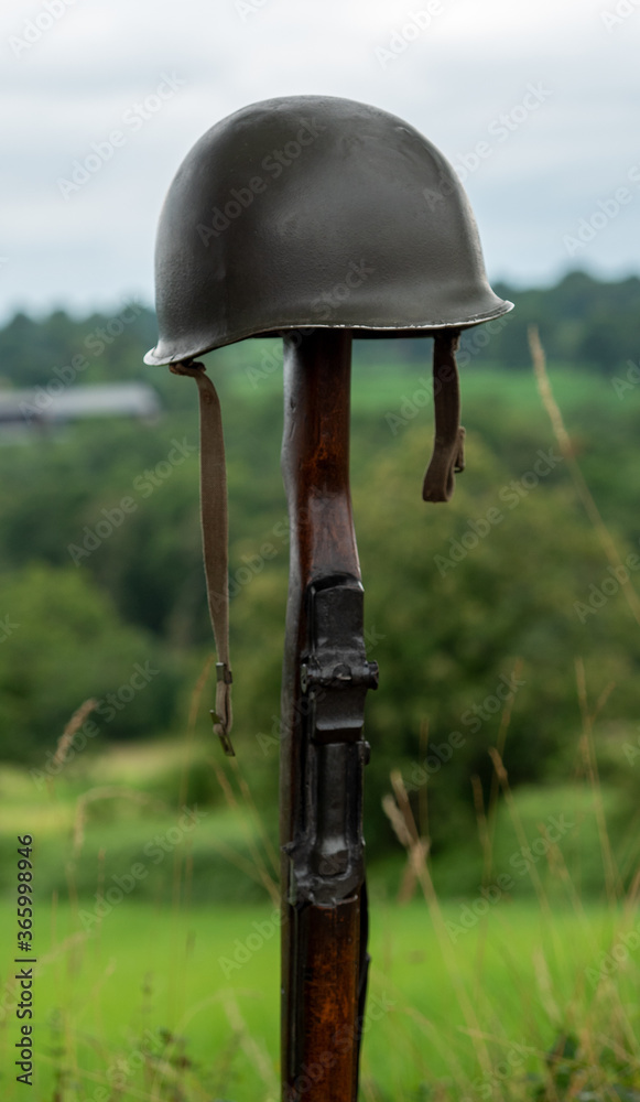 Memorial battlefield cross. Symbol of a fallen US soldier. M1 rifle with helmet.