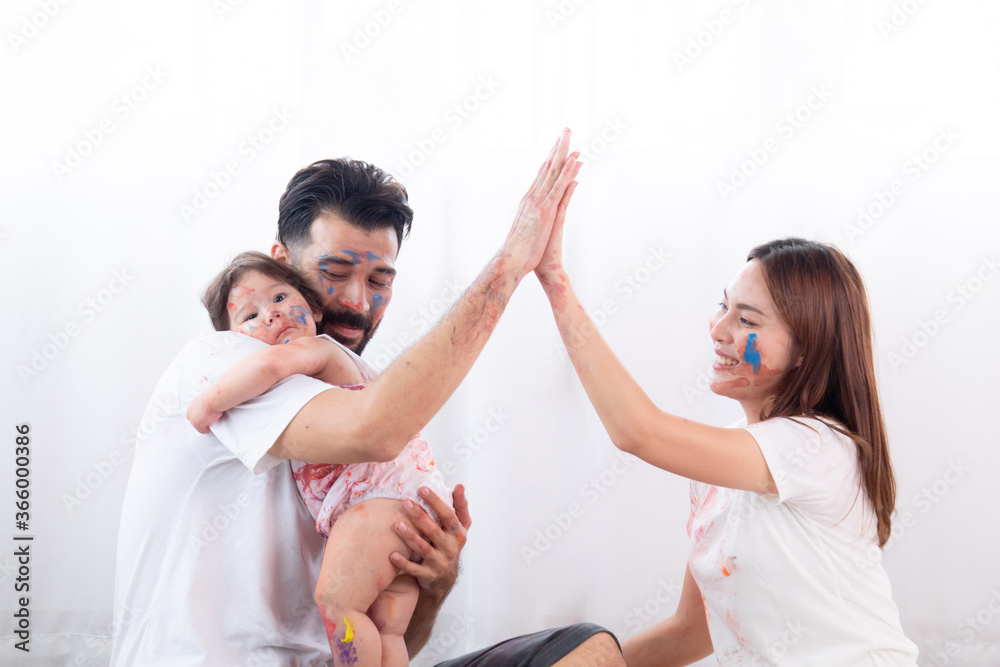 Happy mixed race family and half-Turkish baby girl playing fun together paint face and paper, father, mother, parenthood hug adorable daughter paint color on dirty white clothes, hands and face Happy mixed race family and half-Turkish baby girl playing fun together paint face and paper, father, mother, parenthood hug adorable daughter paint color on dirty white clothes, hands and face