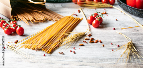 Italienisch kochen Vollkorn Pasta roh und ungekocht mit frischen Tomaten auf einen Holztisch