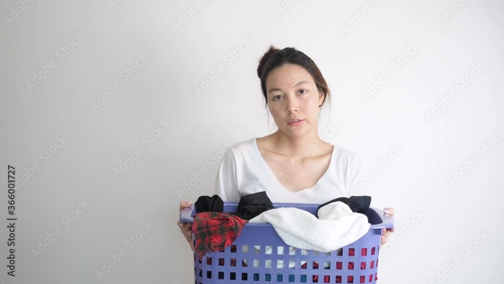 Asian woman holding basket of used clothes for washing. boring face. Concept of housework. Asian woman holding basket of used clothes for washing. boring face. Concept of housework.