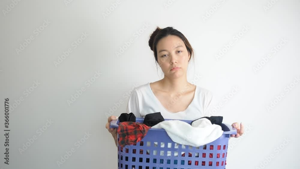 Asian woman holding basket of used clothes for washing. boring face. Concept of housework. Asian woman holding basket of used clothes for washing. boring face. Concept of housework.