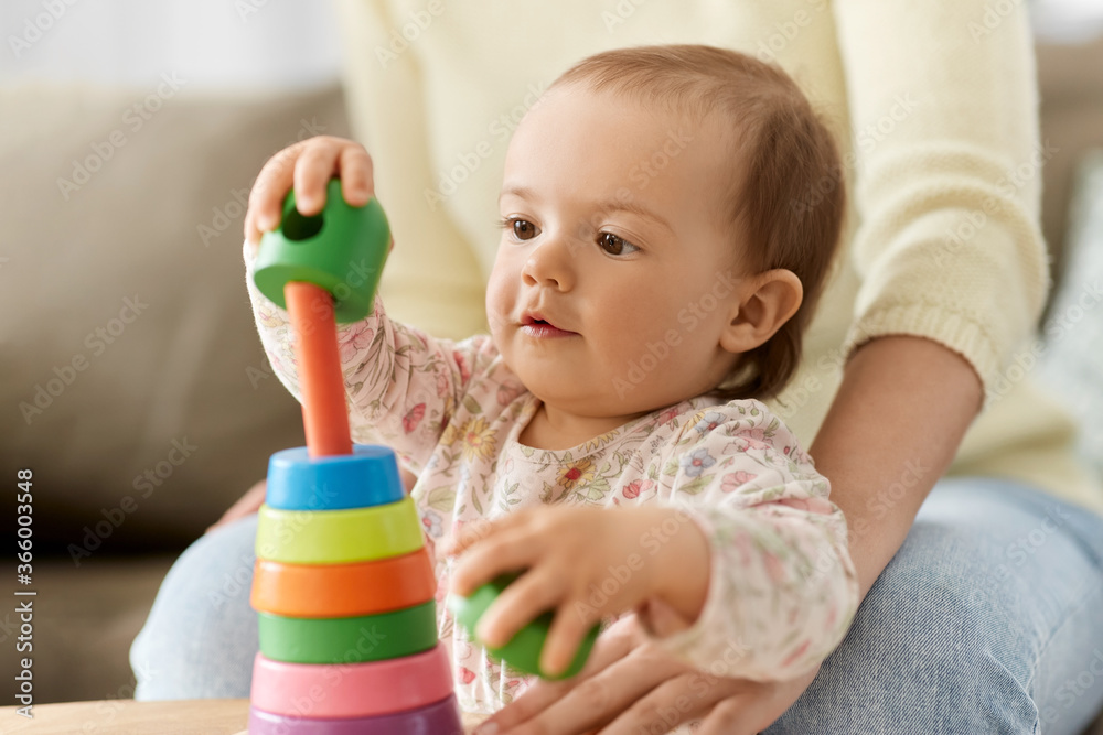 childhood and developing concept - lovely baby girl playing with toy pyramid at home childhood and developing concept - lovely baby girl playing with toy pyramid at home
