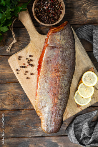 Smoked fish trout. Whole Smoked trout on the serving Board. Smoked trout lay on the wooden kitchen table. Smoked fish close up
