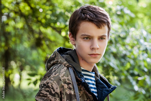 Принти на полотні Teenager boy in a vest and camouflage jacket, portrait outdoors, looking to the