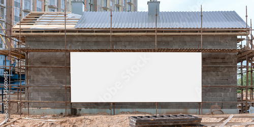 large white empty sign board on wall of temporary house on construction site mock-up scaffold background