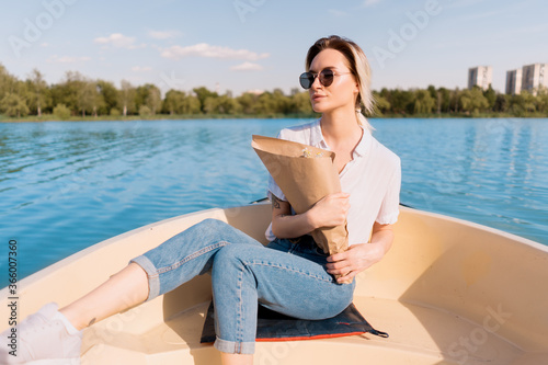 Pretty amazing young woman, blond relaxing on a boat, wearing sunglasses, enjoying her vacation, camomile flowers and amazing time
