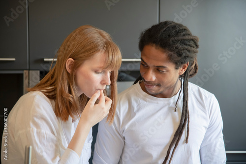 woman touching her lips while a handsome black man looks at her lovingly. Diversity and love concept.
