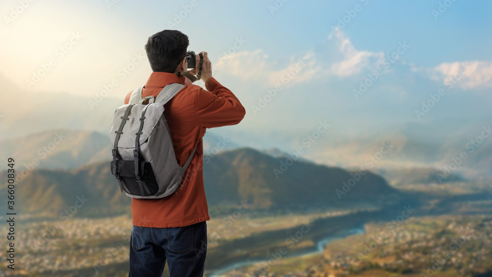 Hipster young asian man on the top of mountain with backpack and take a photo with digital camera the beauty of landscape, Adventure and travel concept, Travelling tour at the Machhapuchhre in Nepal