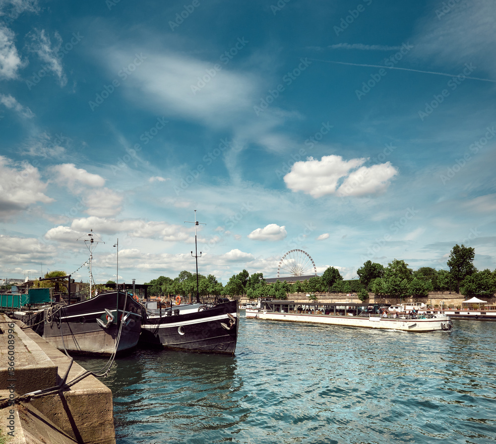 Riverside in Paris, France, panoramic image with boats on river Seine and ferris wheel.