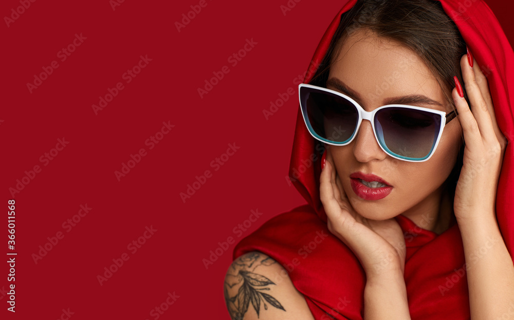 Portrait of gorgeous sexy woman with luxurious make-up in white sunglasses and red headscarf on red background. copy space for text Portrait of gorgeous sexy woman with luxurious make-up in white sunglasses and red headscarf on red background. copy space for text