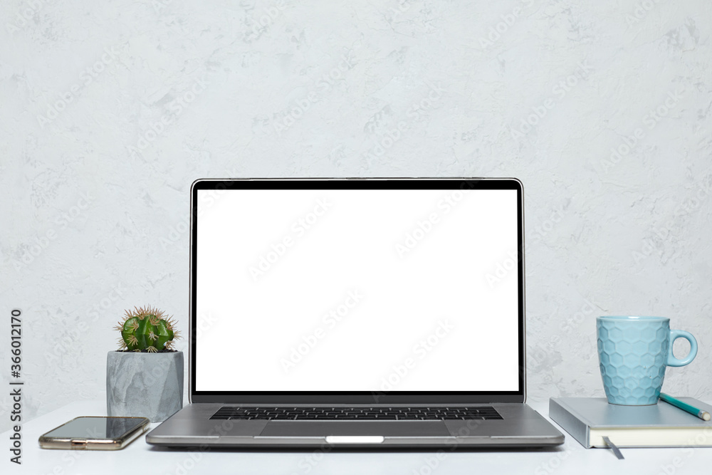 Fototapeta premium open laptop with blank empty screen on white table in interior. mockup