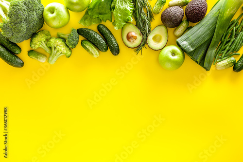 Greeny cocktail ingredients.Green vegetables background. Сucumber, avocado, broccoli, beans, leek and fresh apple on Yellow background top view
