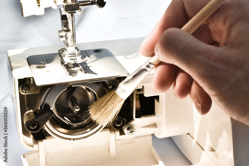 Cleaning and preparation of sewing machine. A woman uses a brush