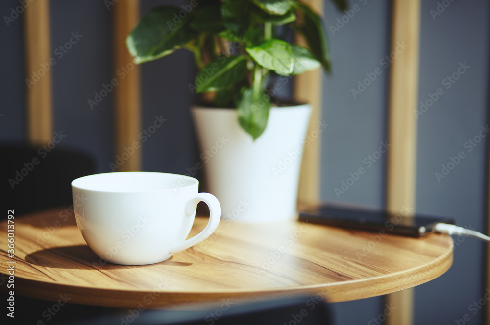 Empty white cup and smart phone on table in cafe. Morning light falls from the window.Coffee break.Blurred image,selective focus Empty white cup and smart phone on table in cafe. Morning light falls from the window.Coffee break.Blurred image,selective focus