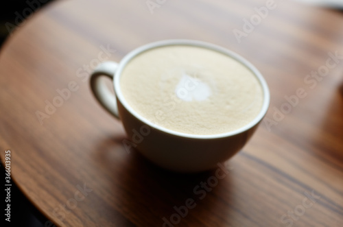 
Blurred image of cup of coffee latte on table in cafe. Morning light falls from the window.Coffee break