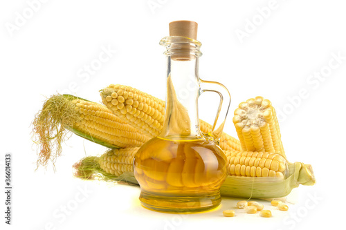 Corn oil in a carafe, peeled corn cobs and grains, text space isolated on a white background