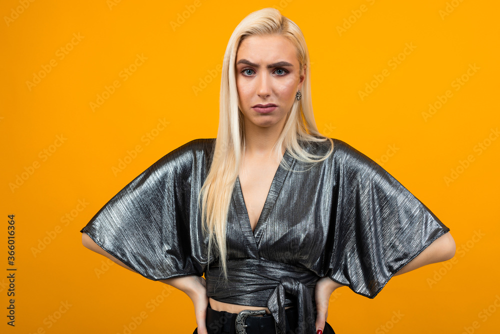 Fototapeta premium portrait of a blonde attractive displeased young woman on yellow studio background