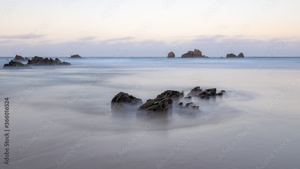 olas rodeando roca en la playa