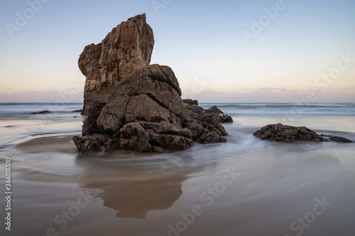 Corriente de agua rodeando roca en la playa © bra