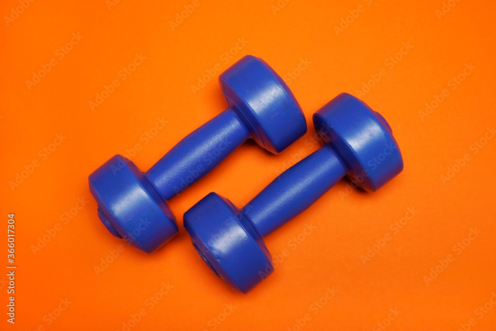 Weights to practice exercise at home. Fit and strong arms. Home or gym sport equipment. Dumbbell for fitness workout. Strength concept. Weights to practice exercise at home. Fit and strong arms. Home or gym sport equipment. Dumbbell for fitness workout. Strength concept.