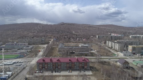Aerial view of Karabash city with three-story and five-story houses. Spring, trees without leaves. At the background the Ural mountains. Russia, Chelyabinsk region
