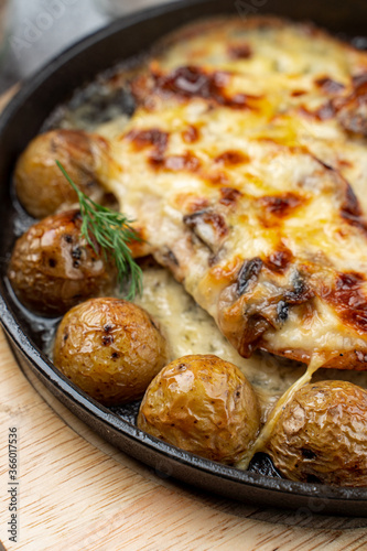 Mouthwatering pub dish in cast iron  baked baby potato with poultry and cheese crust