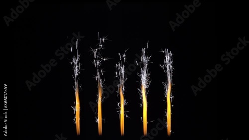 Traces of glowing hot particles. Five cold sparkling Bengal fountains on black. 5th anniversary concept. Decoration for video editing, overlay on a cake. Stream of fire sparks on a dark.
