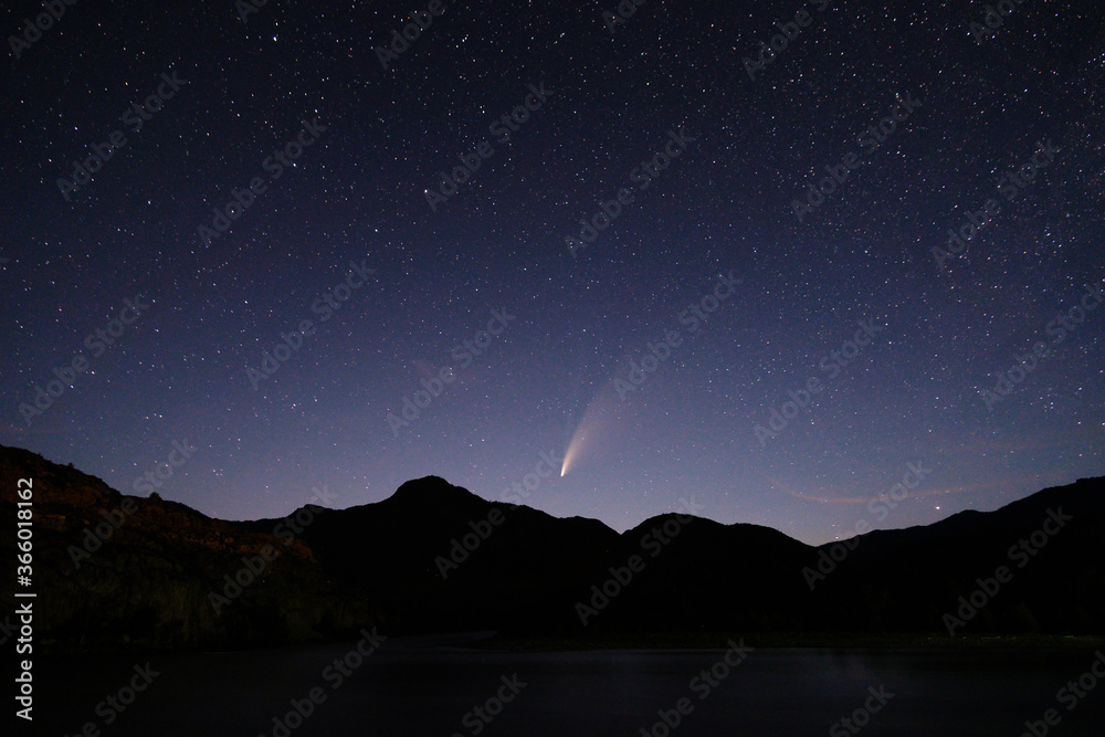 Comet C / 2020 F3 (NEOWISE) in the light of the setting sun over a mountain valley. Astro photography, Altai, Russia.