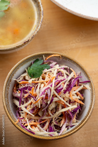 A bowl of cabbage salad with red and white cabbage, grated carrot and herbs