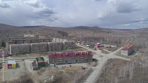 Aerial view of Karabash city with three-story and five-story houses. Spring, trees without leaves. At the background the Ural mountains. Russia, Chelyabinsk region
