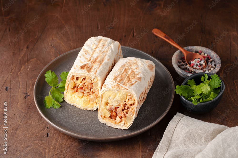 A cut Chicken doner kebab in roll of pita bread lavash. Shawarma Sandwich on a wooden background
