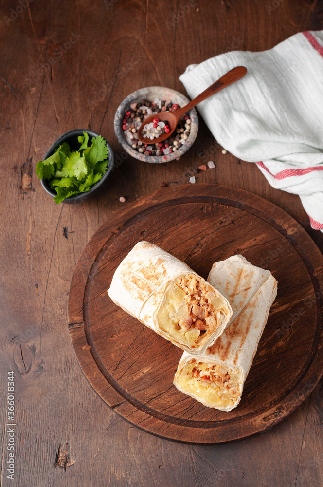 A cut Chicken doner kebab in roll of pita bread lavash. Shawarma Sandwich on a wooden background