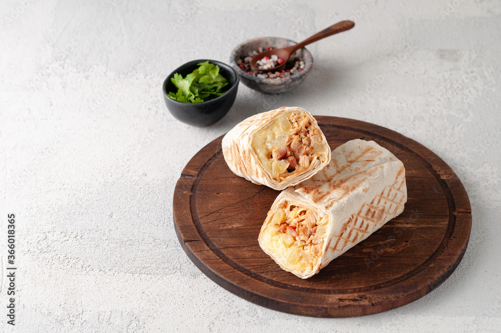 A cut Chicken doner kebab in roll of pita bread lavash. Shawarma Sandwich on a light grey background