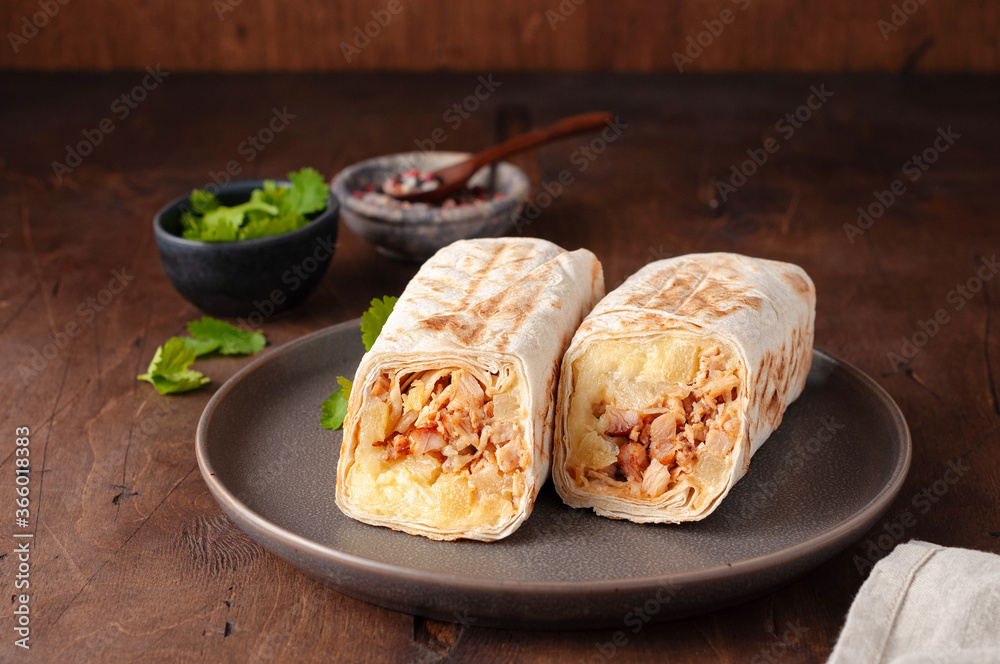 A cut Chicken doner kebab in roll of pita bread lavash. Shawarma Sandwich on a wooden background