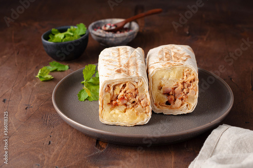 A cut Chicken doner kebab in roll of pita bread lavash. Shawarma Sandwich on a wooden background