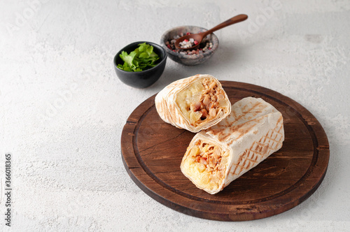 A cut Chicken doner kebab in roll of pita bread lavash. Shawarma Sandwich on a light grey background