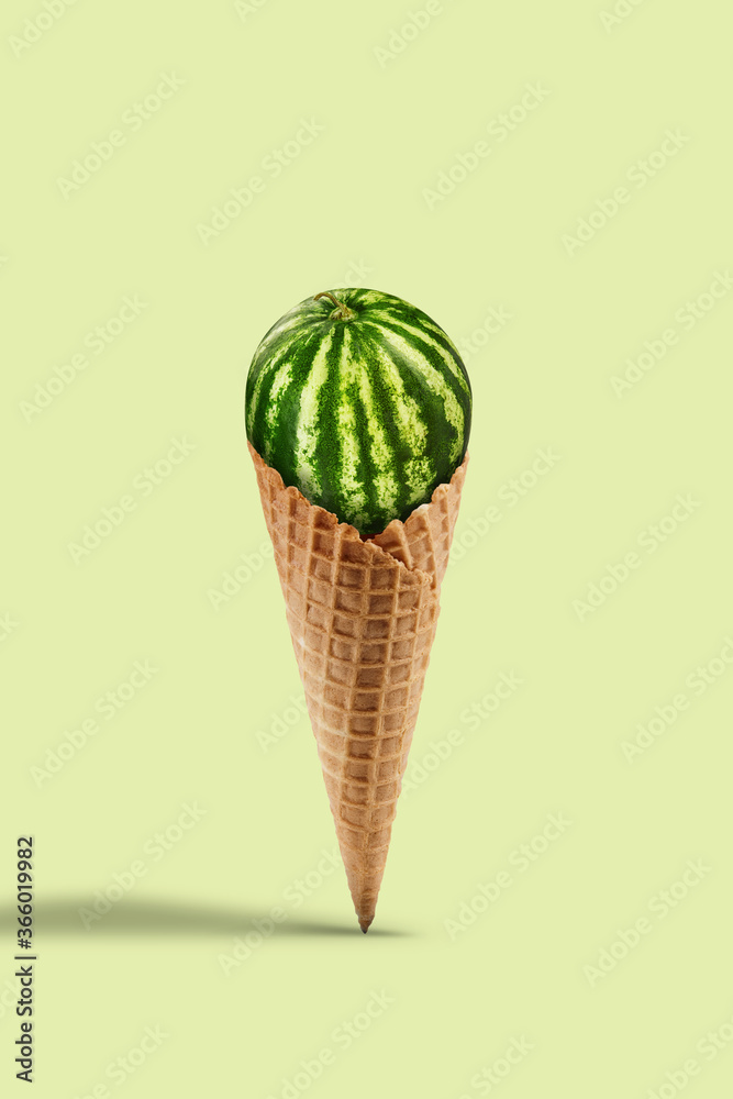 Green watermelon in sweet wafer cone on yellow background. Healthy nutrition, food, seasonal harvest of berries and fruits. Close up, copy space Green watermelon in sweet wafer cone on yellow background. Healthy nutrition, food, seasonal harvest of berries and fruits. Close up, copy space