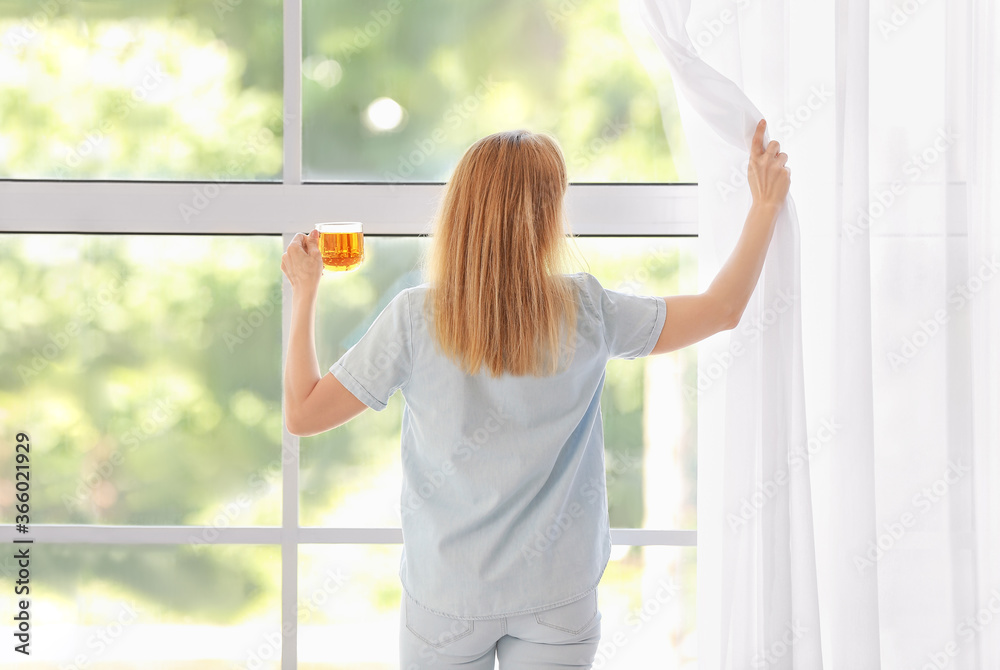 Beautiful woman drinking tea near window at home Beautiful woman drinking tea near window at home