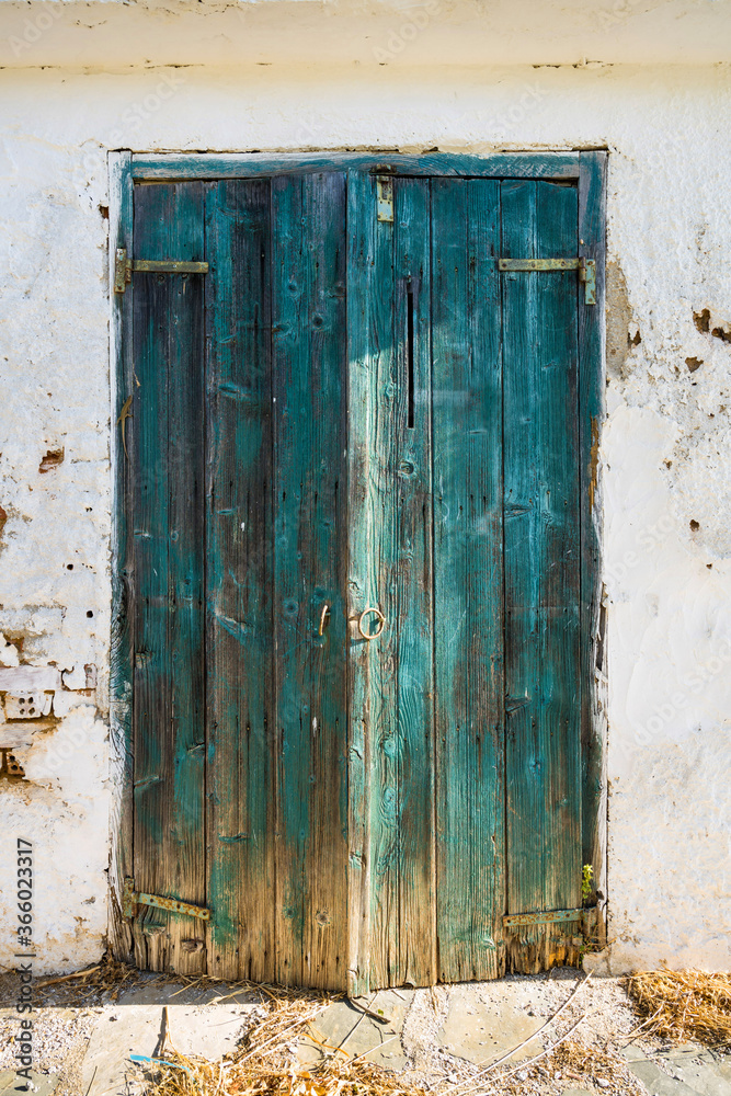 An old turquoise wooden door from a white shed with vintage charm. An old turquoise wooden door from a white shed with vintage charm.