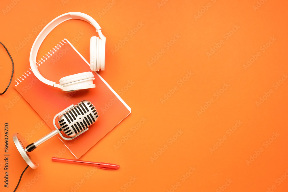 Headphones with microphone and notebook on color background Headphones with microphone and notebook on color background