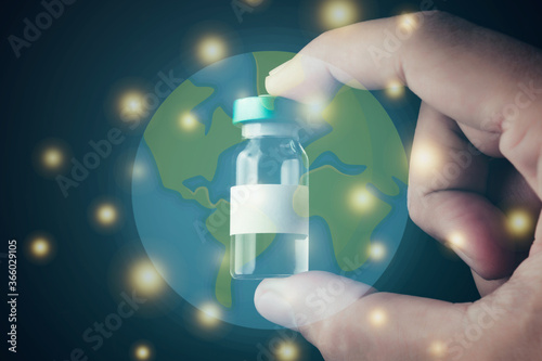 An Asian man's hand is holding a vaccine bottle with a white label with space to fill the message. With a translucent and twinkling world as the background
