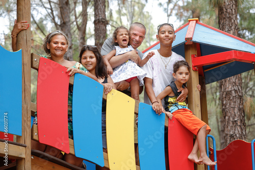 Bellissima famiglia Multientinica Italo - Brasiliana si raduna in un gruppo sopra una struttura colorata di giochi per bambini photo