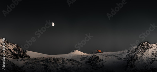Der Mond schein über am nächtlichen Himmel über dem Gipfel des Col de Rosses in den schweizer Alpen  photo