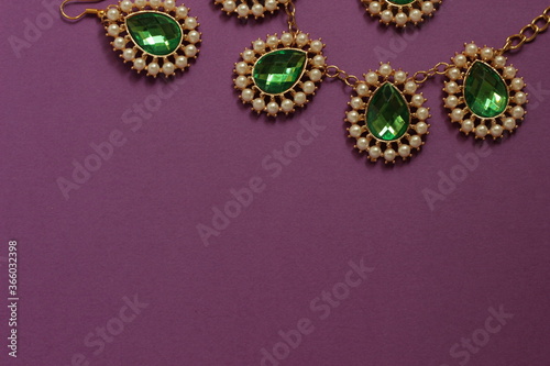 luxury green jewelry in the Baroque style on a purple background. Vintage, retro style.
copy space
