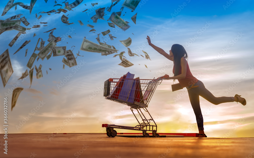 Φωτογραφία Shopping woman in action of chasing money spending with  shopping cart pushing,