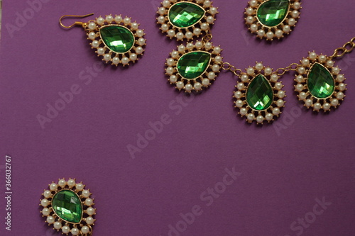 luxury green jewelry in the Baroque style on a purple background. Vintage, retro style.
copy space
