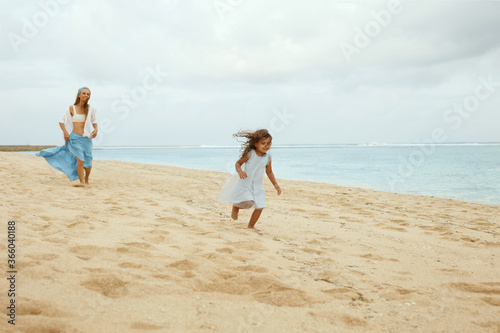 Beach Vacation. Family Walking Along Ocean Coast. Kids And Young Woman In Maxi Skirt Enjoying Summer Weekend At Tropical Resort. Mother And Daughter Having Fun.